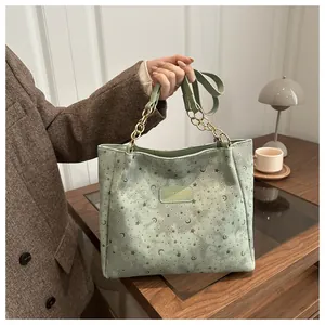 Dettaglio borsa tote verde menta con motivi di stelle e lune e manico a catena in metallo