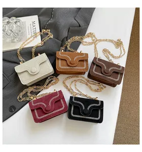 Detail view of five suede mini crossbody bags with decorative white stitching and gold chains