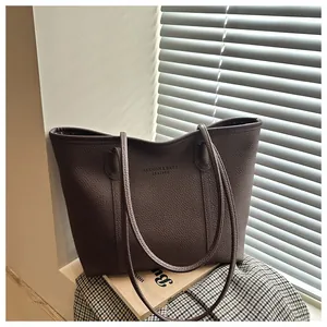 Detail of dark brown tote bag featuring pebbled leather texture and long shoulder straps