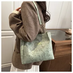 Dettaglio borsa shopper verde chiaro con motivi di stelle e luna su tessuto scamosciato