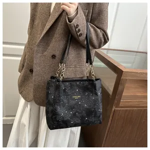 Dettaglio della borsa nera con stampa di stelle e lune e catena dorata elegante