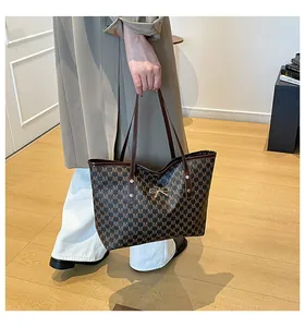 Détail d'un sac cabas marron à monogramme avec boucle noeud dorée et anses en cuir
