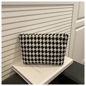 Macro view of woven black and white diamond pattern on a stylish handheld clutch bag
