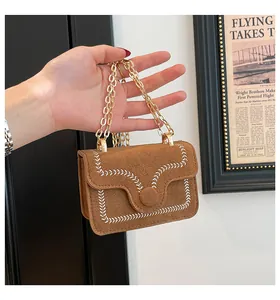Detail of brown suede mini bag featuring white embroidery and elegant gold chain strap