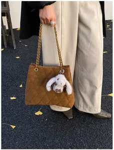 Detail van caramel gewatteerde tote bag met gouden ketting en pluche konijnenhanger