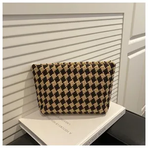 Detail of geometric pattern woven clutch bag with textured fabric on white books