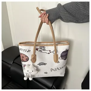 Dettaglio della borsa tote in tela con graffiti di astronauti e finiture in pelle marrone