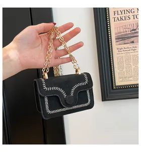 Close-up of black matte chain bag featuring white leaf embroidery and gold metal hardware