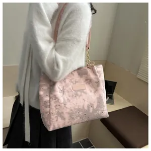 Dettaglio borsa shopper rosa con motivi di stelle e lune indossata da modella