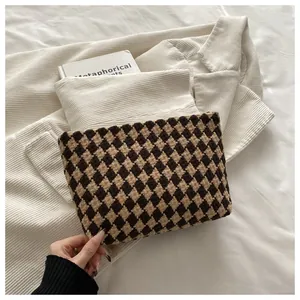 Detailed view of the woven brown checkerboard clutch on soft corduroy fabric