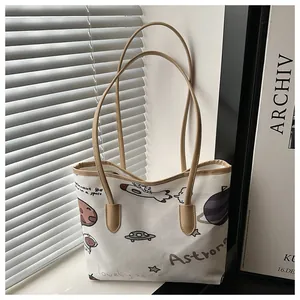Dettaglio delle illustrazioni spaziali e manici kaki sulla borsa tote in tela