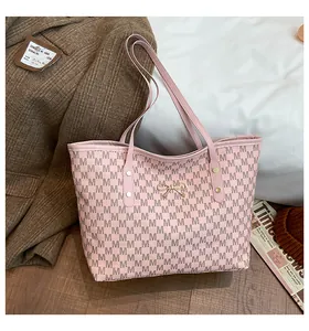 Détail du sac cabas rose avec imprimés M et nœud doré sur fond de tenue élégante