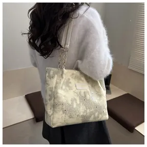 Dettaglio della borsa tote bianco sporco con motivi di luna e stelle oro e tracolla a catena
