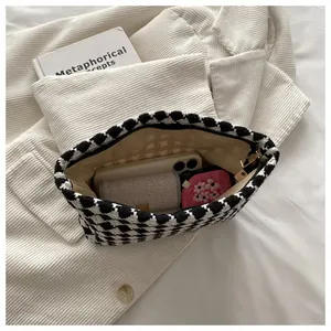 Detail view of houndstooth clutch bag showing interior capacity and golden zipper