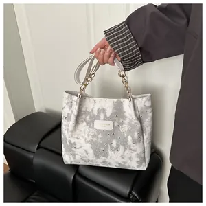Dettaglio stampe stella e luna su borsa tote tie-dye con catena in metallo dorato