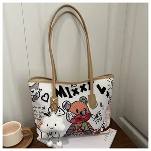 Dettaglio della borsa tote in tela bianca con graffiti di orso e ciondolo a nuvola