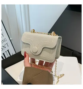 Macro detail of beige suede mini bag featuring exquisite stitching and gold chain strap