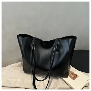 Close-up of sleek black PU leather tote bag with fine stitching and slim shoulder straps