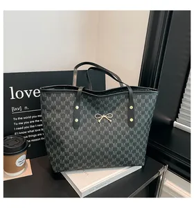 Gros plan sur un sac cabas à carreaux gris avec nœud en métal doré et anses en cuir
