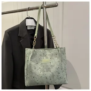 Dettaglio borsa tote verde chiaro con motivi luna stella e catena dorata