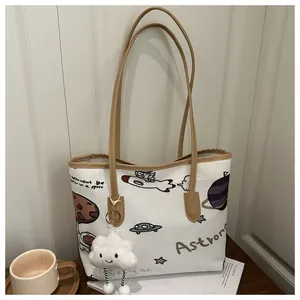 Dettaglio borsa tote in tela con disegni spaziali e ciondolo a forma di nuvola