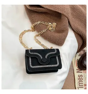 Detail of black crossbody bag with white embroidery stitching and golden chain strap