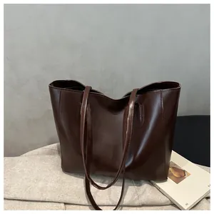 Detailed close-up of dark brown leather tote bag with elegant handles and smooth finish