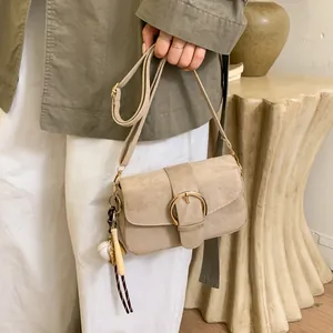 Detail of apricot crossbody bag with gold ring clasp and baseball themed pendant accessory