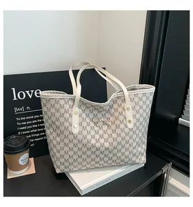 Détail du cabas monogramme avec nœud doré et poignée en cuir sur un bureau élégant