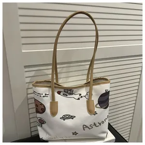 Dettaglio della borsa tote in tela con motivi graffiti di astronauti e manici in pelle