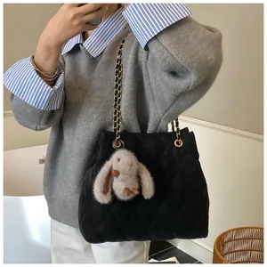 Detail van zwarte gewatteerde shopper met gouden ketting en schattige pluche konijn hanger