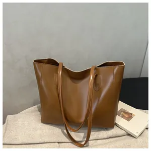 Detailed close-up of brown PU leather tote bag featuring glossy texture and long strap