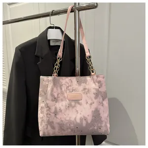 Dettaglio della borsa tote rosa tie-dye con catena dorata e motivi celesti di stelle e luna
