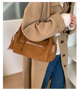 Close-up of brown suede shoulder bag with zipper pockets and long leather strap