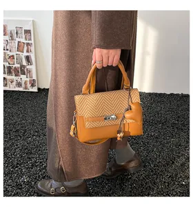 Detail of plaid woven fabric texture and metal twist lock on the brown crossbody bag