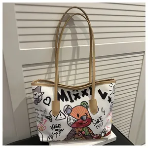 Dettaglio della borsa tote in tela bianca con graffiti di orsi colorati e tracolla marrone
