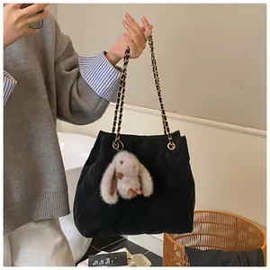 Detail van zwarte gewatteerde shopper met kettingriem en schattige grijze konijnenhanger