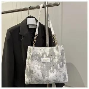 Dettaglio della borsa tote con motivo stelle e luna, catena e logo del marchio