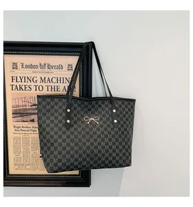 Détail du sac cabas gris foncé avec motif jacquard lettre M et décoration nœud doré