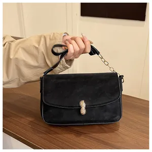 Detail view of the black crossbody bag showing a unique golden peanut-shaped metal twist lock