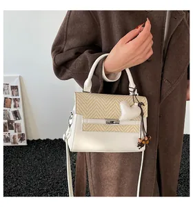 Detail of crossbody bag with beige faux leather, woven texture, and heart charm accessory