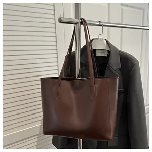 Detail view of deep brown leather tote bag hanging with grey blazer in business style