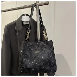 Dettaglio borsa shopper nera con stampa stelle e luna e tracolla a catena
