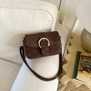 Detail of vintage brown suede crossbody bag featuring a classic gold circular buckle lock