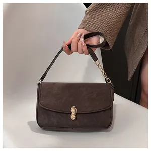Detailed close-up of textured matte brown leather bag with golden peanut-shaped buckle