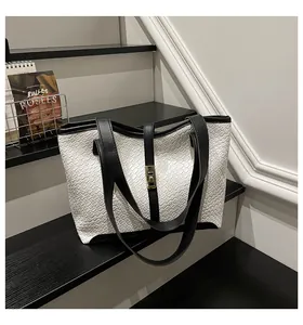 Detailed macro view of woven faux leather texture and gold clasp on black and white tote bag