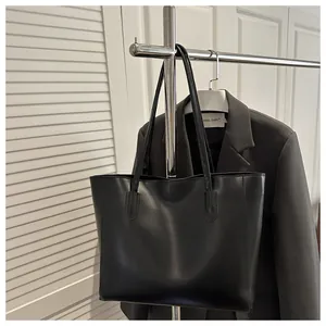 Macro view of black tote bag hanging on metal hanger with refined leather texture detail