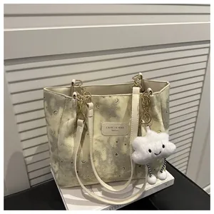 Dettaglio della borsa tote con stampa stelle, catena dorata e ciondolo a nuvola