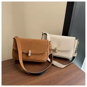 Close-up of golden peanut-shaped clasp and wide shoulder strap on fashion handbag