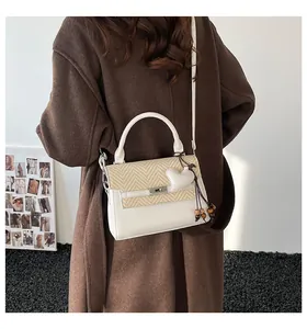 Detail of crossbody bag with woven straw flap, silver lock, and heart charm detail